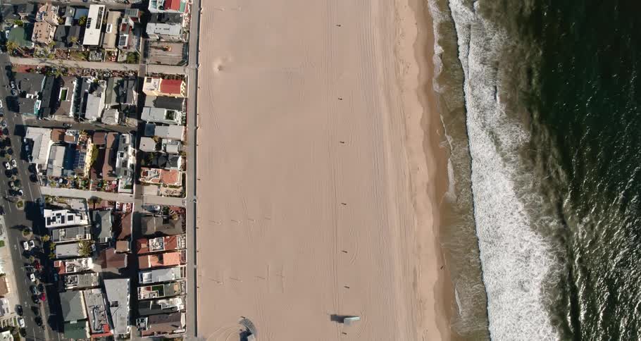 Aerial view coastal city and empty beach next to the wavy sea