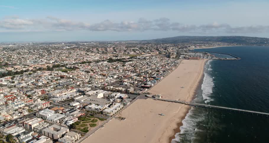 Waves from the ocean roll in towards the sandy beach near the city