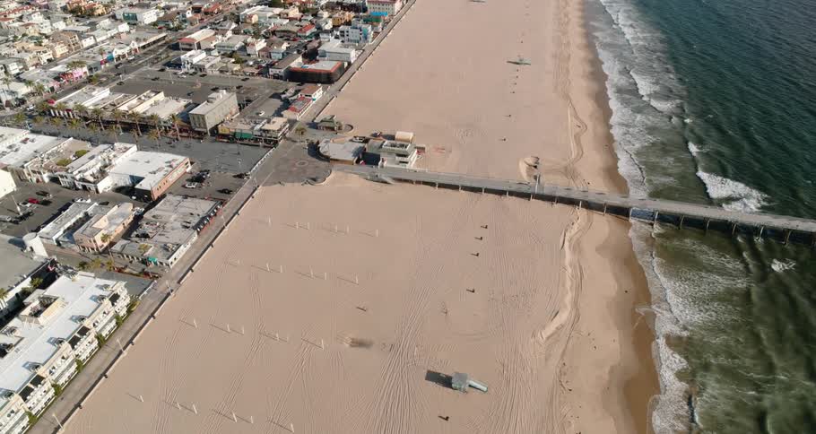 Pier reaches from buildings across beach into ocean