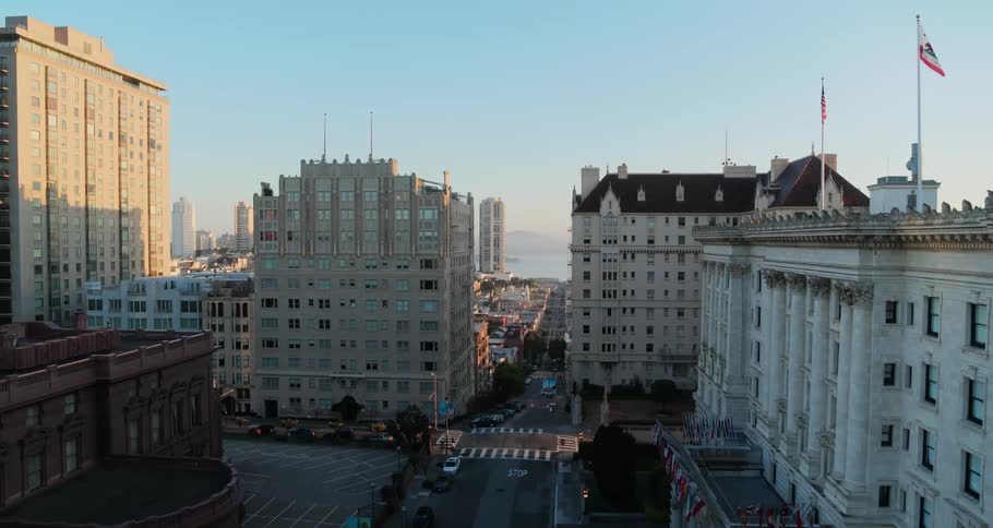 Flags on poles on top of a city building waves softly in the wind above empty city streets