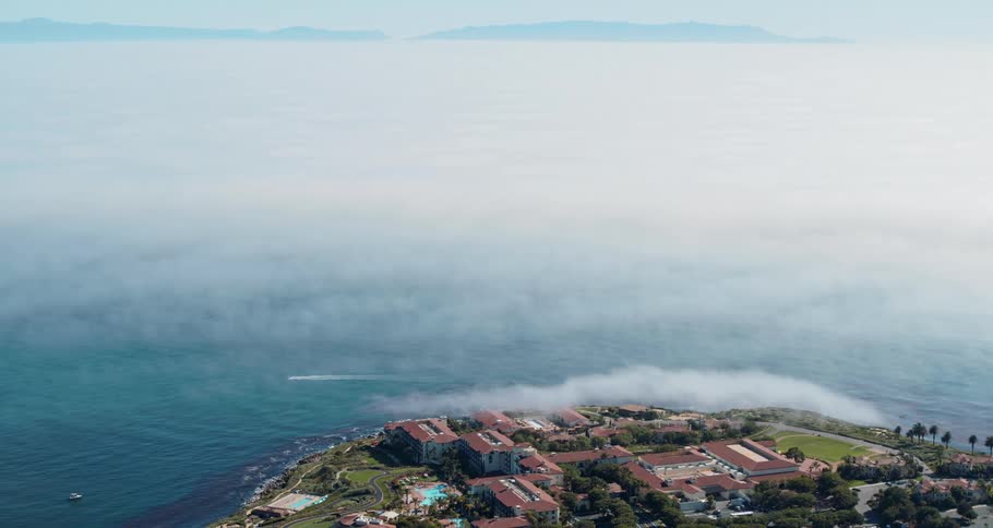 Fog obscures ocean between building complex and opposite shore