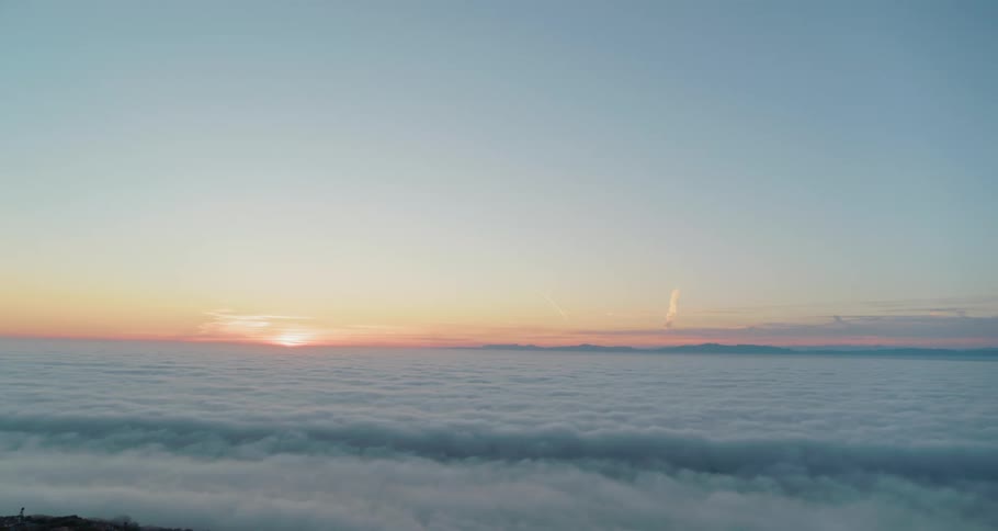 The sun rises over dense clouds in the sky