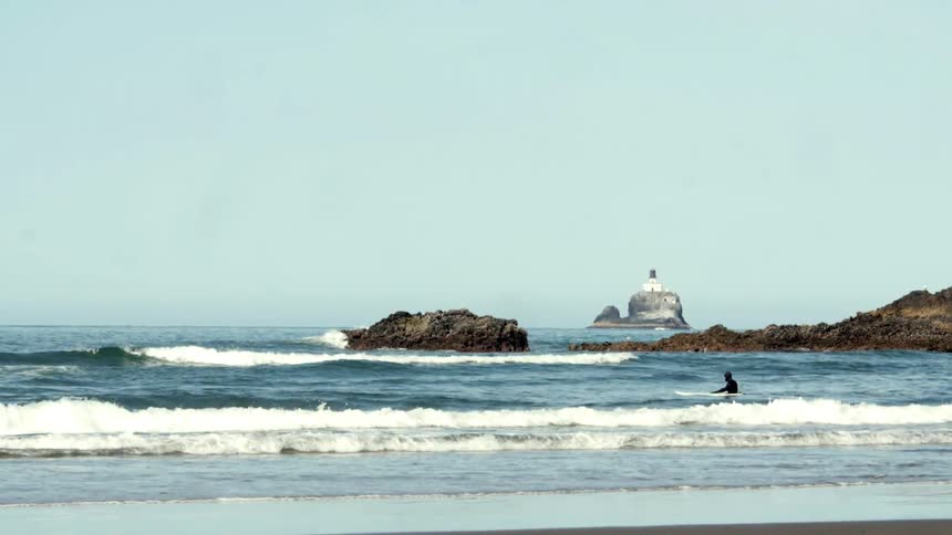 A surfer is floating in the water near the shore of a beach