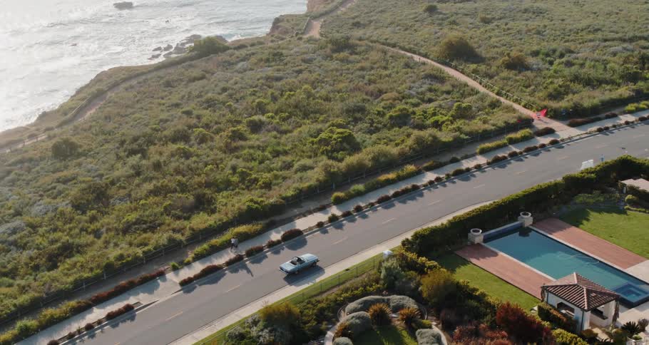 A person is driving on the road by the shore