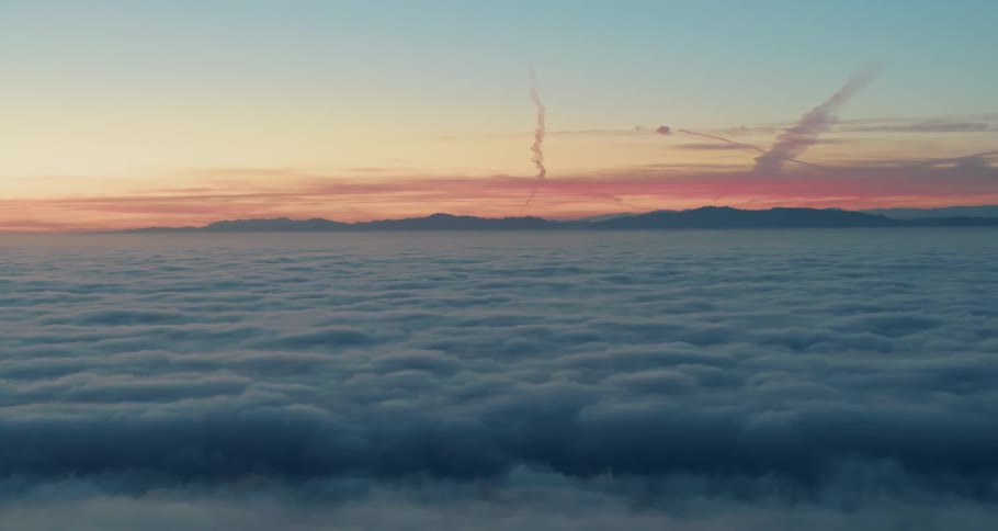 The sun rises over dense fluffy clouds