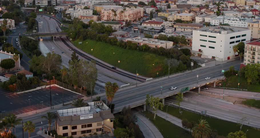 Traffic passes over and under overpass spanning between low rise buildings in city