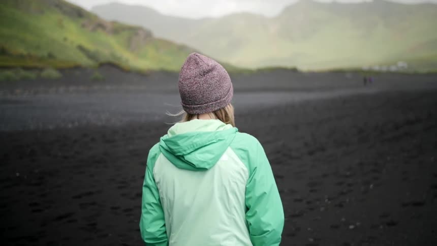 A woman walking on a muddy river shoreline