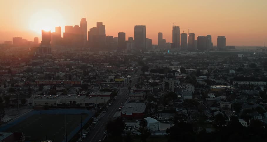 Aerial view of the distant city skyline and the sun rising in the sky