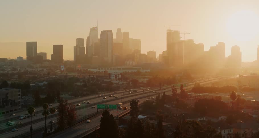 Aerial view of the city skyline and cars moving along highway at sunset