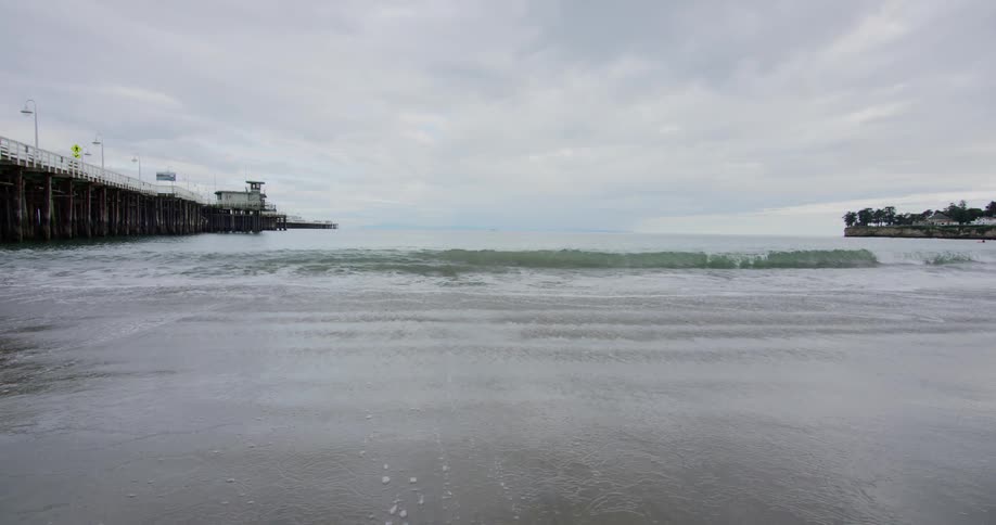 The ocean waves roll into shore near the pier