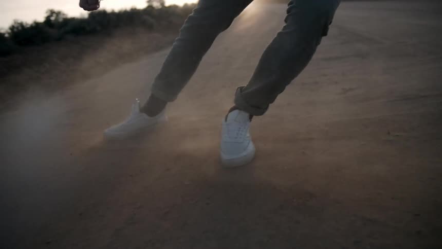 A person slides over a dirt path at sunset