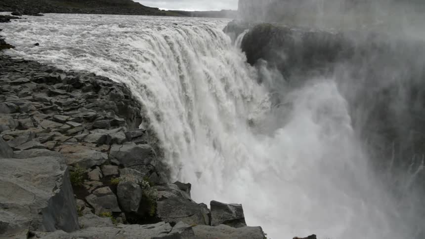A large amount of water cascades over cliff as a waterfall