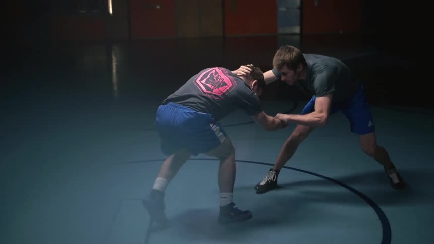 Two men wrestle in a school gym