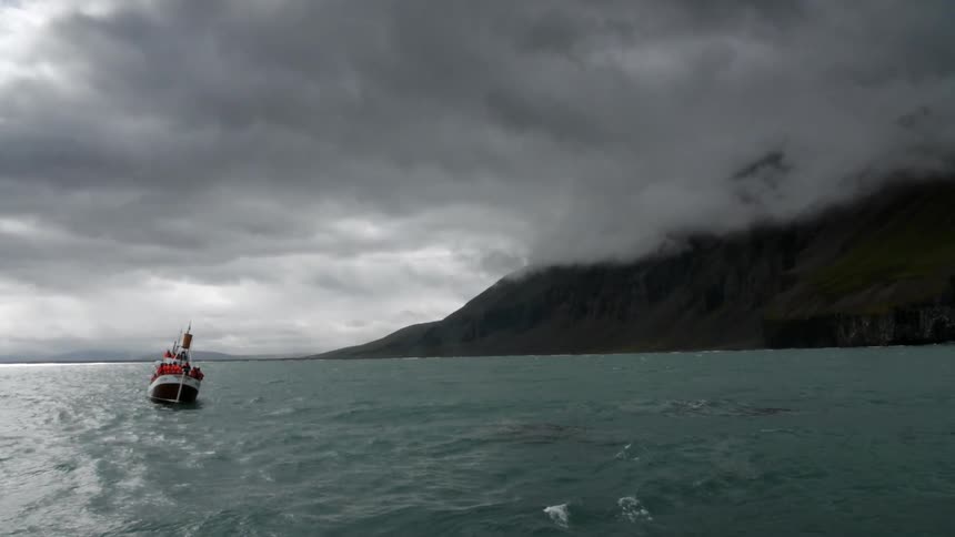 A boat sailing on choppy water under a cloudy sky