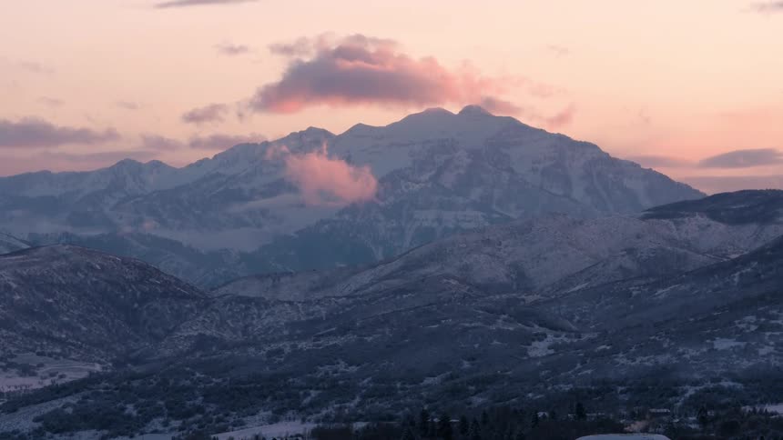 Clouds float over snowy mountains