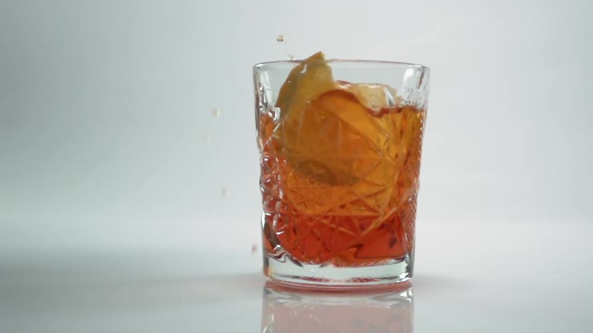 A lime slice falling into a glass of old fashioned