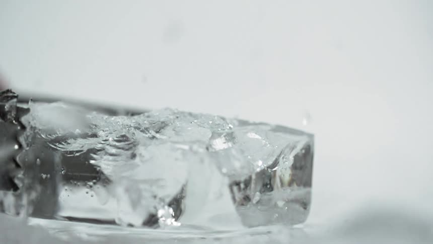 Metal fork shatters ice cube causing chips to fly into air