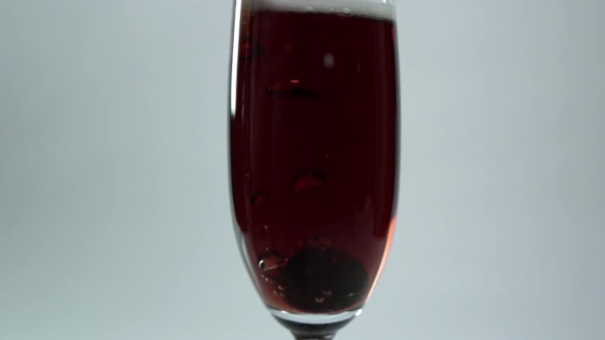 Black olive falls into a glass of red wine