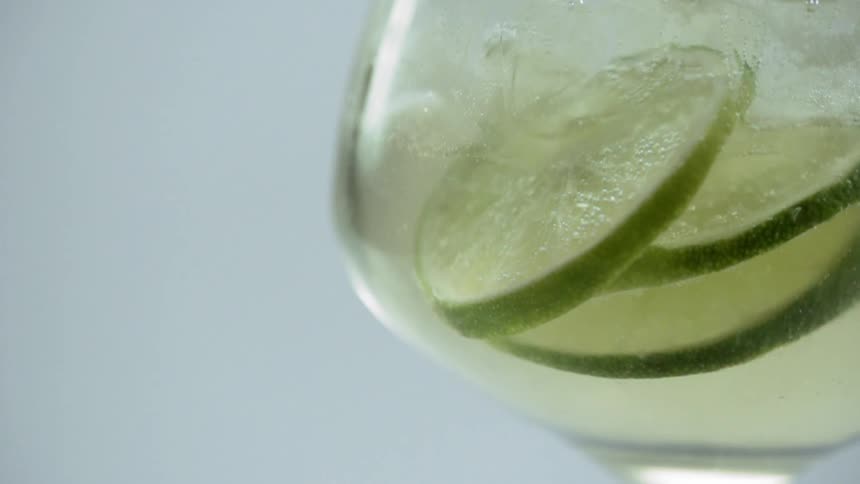 Slices of lime in a the button of a wine glass filled with clear liquid