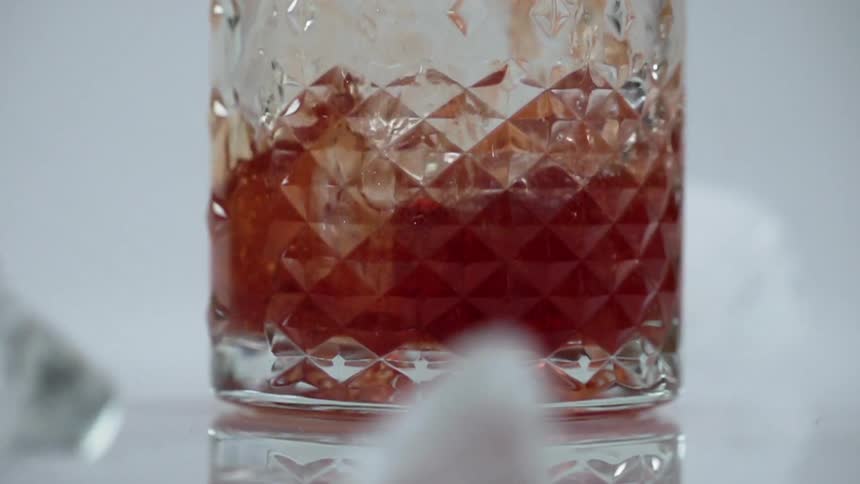 Ice cubes fall in a glass of liquor and outside the glass