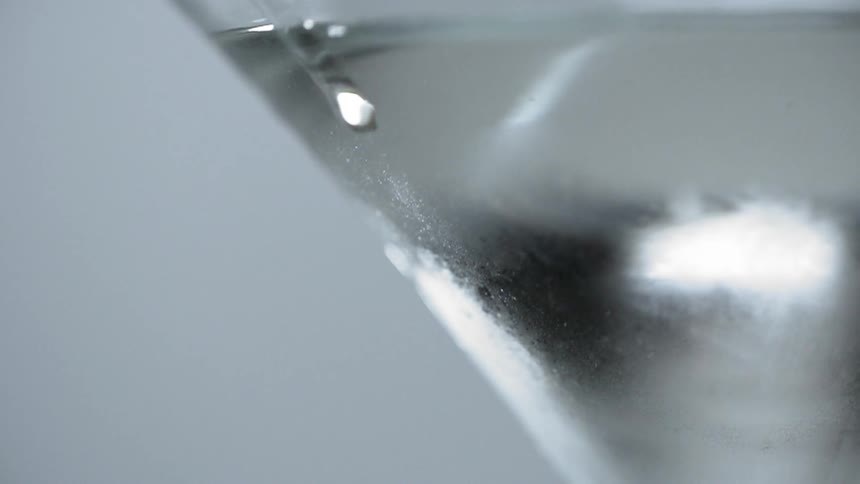 Drop flows down side of glass reflecting light