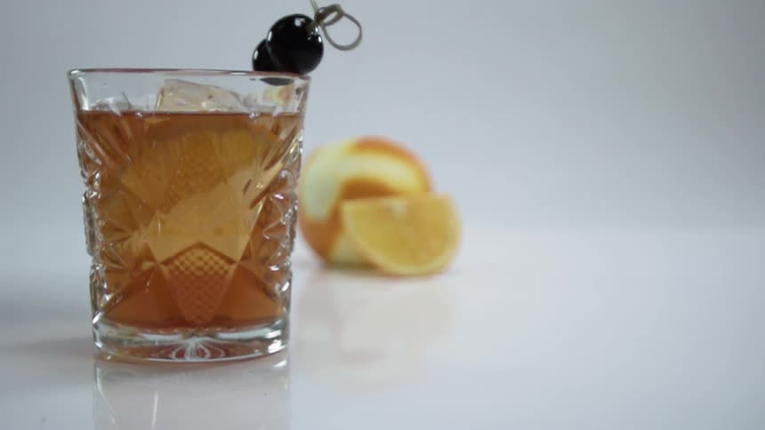 Two black olives stuck on a pick drop into a glass with liquid in it