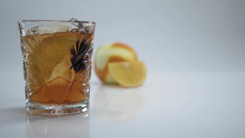 Olives on a pick dropping into a cocktail in slow motion