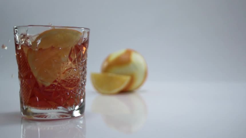 The orange wedge is dropped into the drink