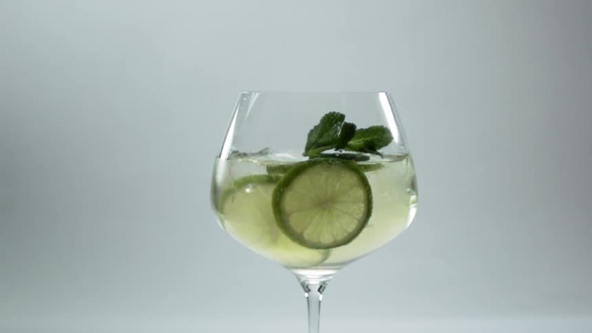 A mint leaf garnish is dropped into a cocktail