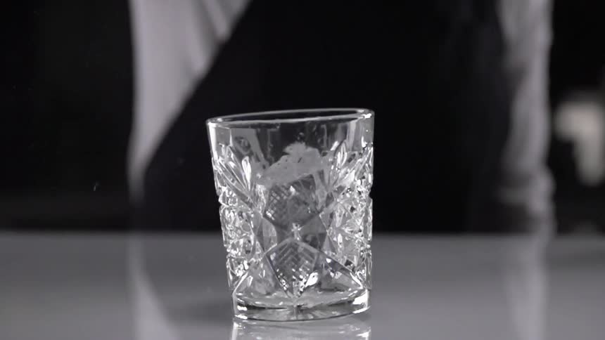 A spinning ice cube falling into a drinking glass