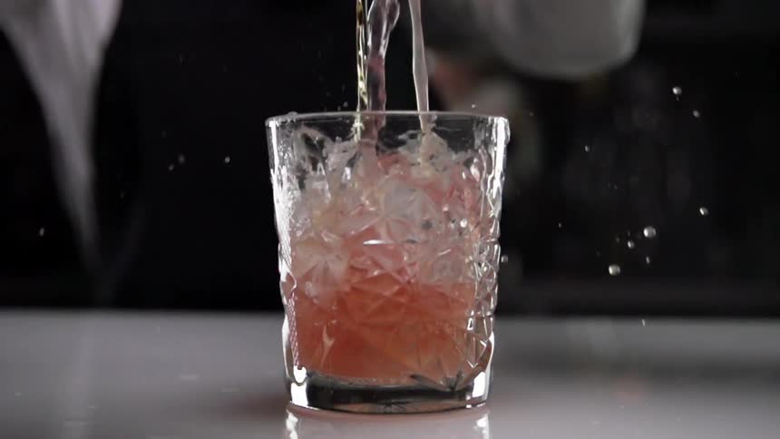 Bartender pours cocktail into a glass in a bar