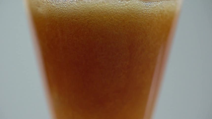 A glass of beer foams up as more beer is poured into it