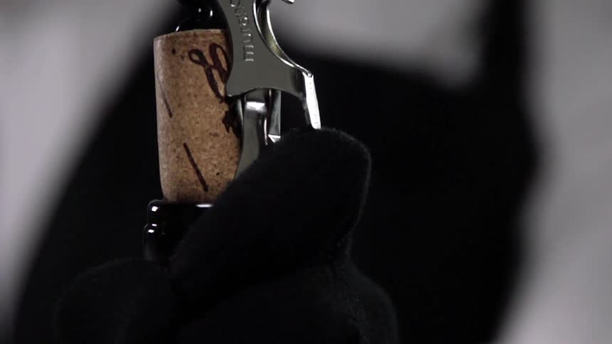 A bartender uncorks a bottle