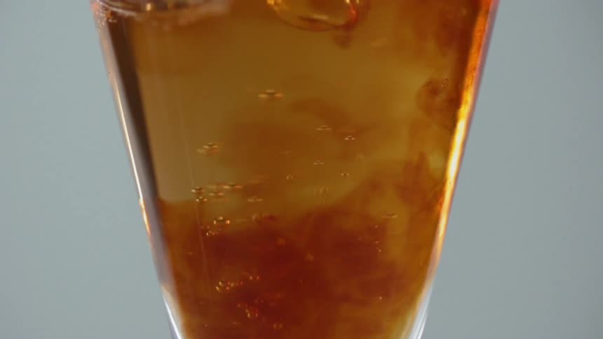 The liquid pours into the glass mixing around