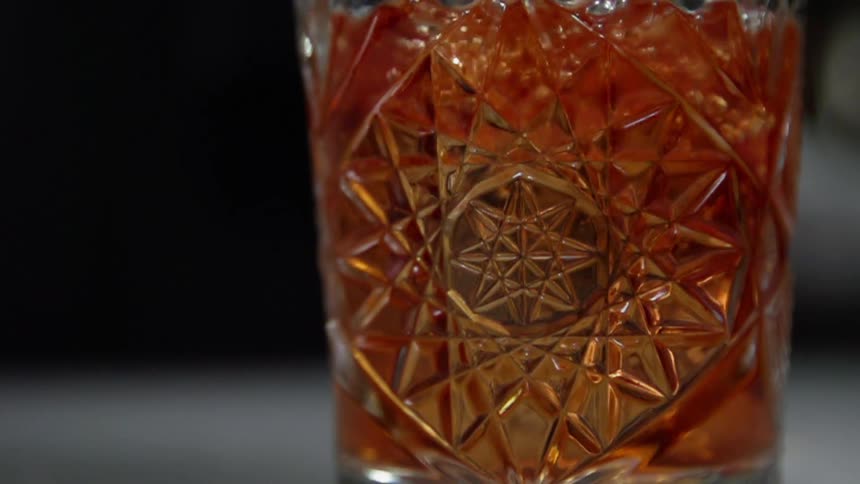 A clear glass is filled with an amber liquid