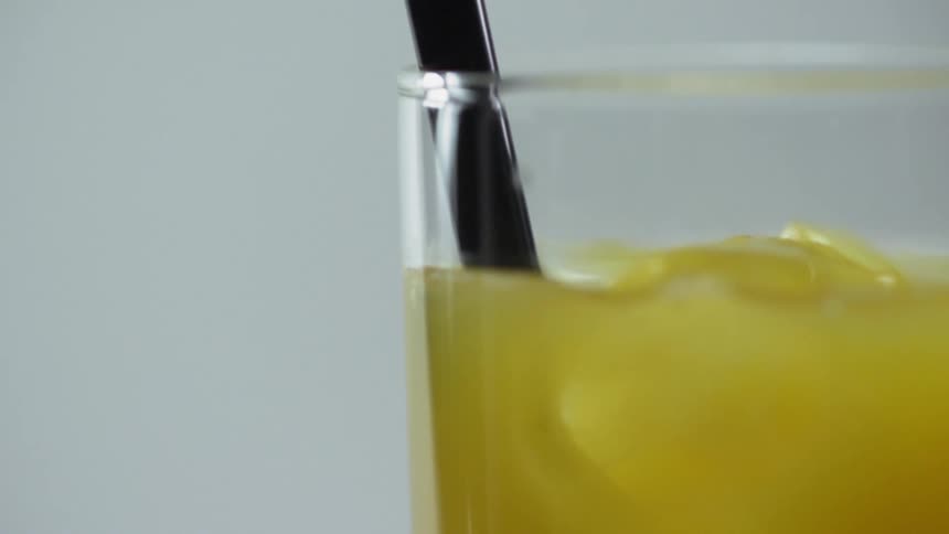 Black cocktail straw is being put into a glass of cocktail
