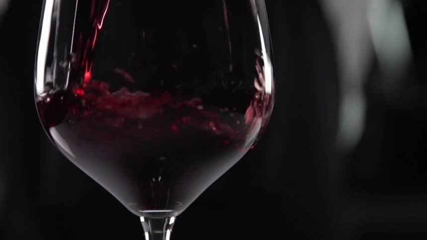 A bartender fills a glass with red wine
