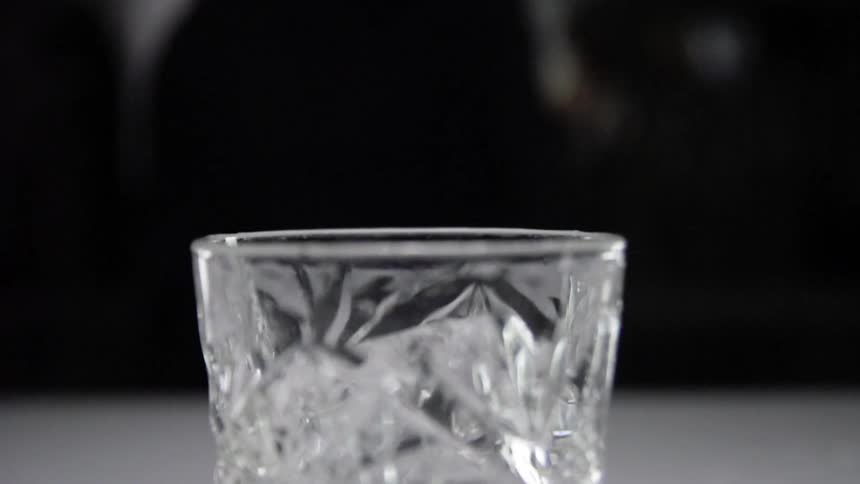An ice cube falling into a glass
