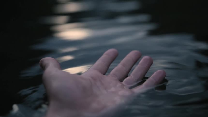 A hand is floating face up in water
