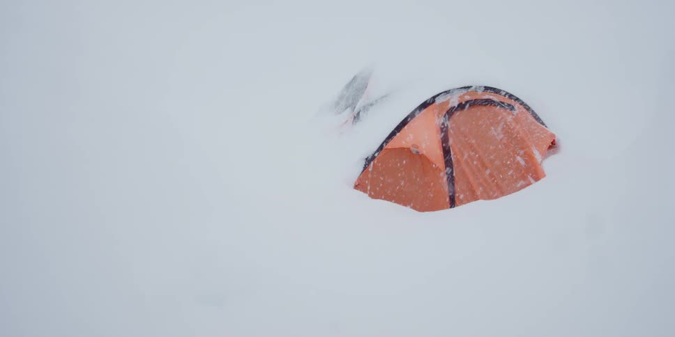 Deep snow covers a tent