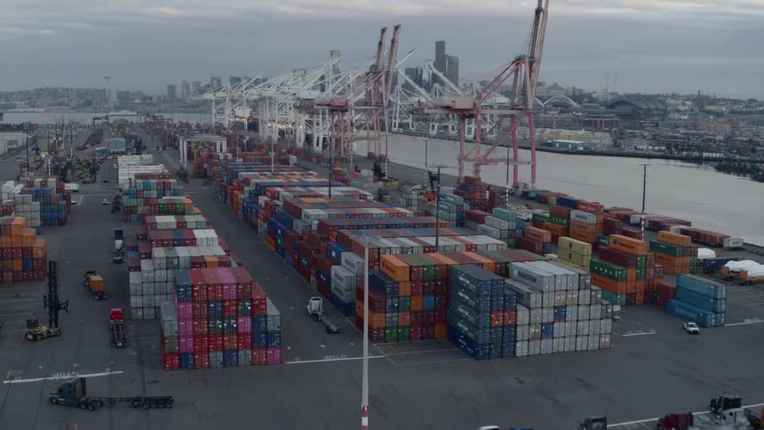 Flying over a large cargo container facility bustling with activity