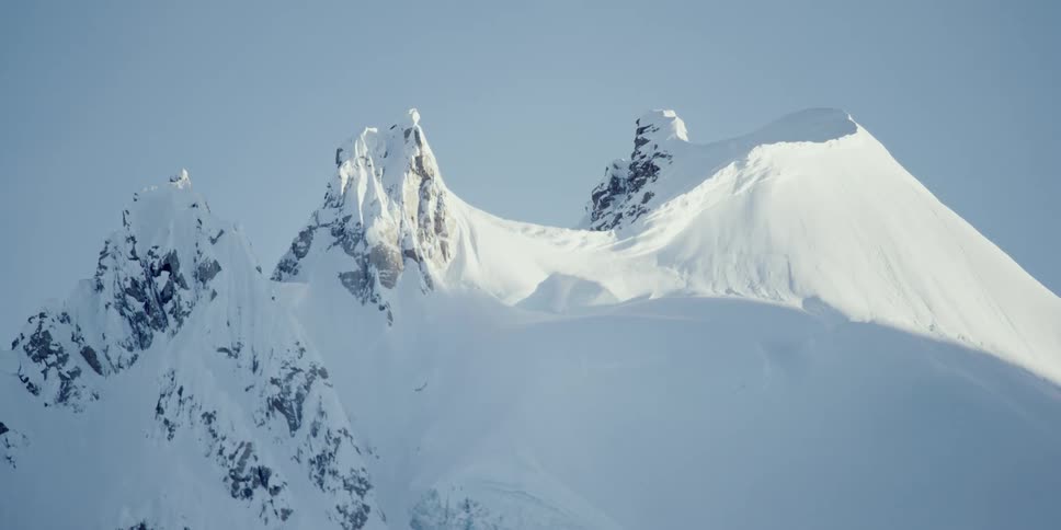 Shadows move across a steep snow covered mountain side timelapse