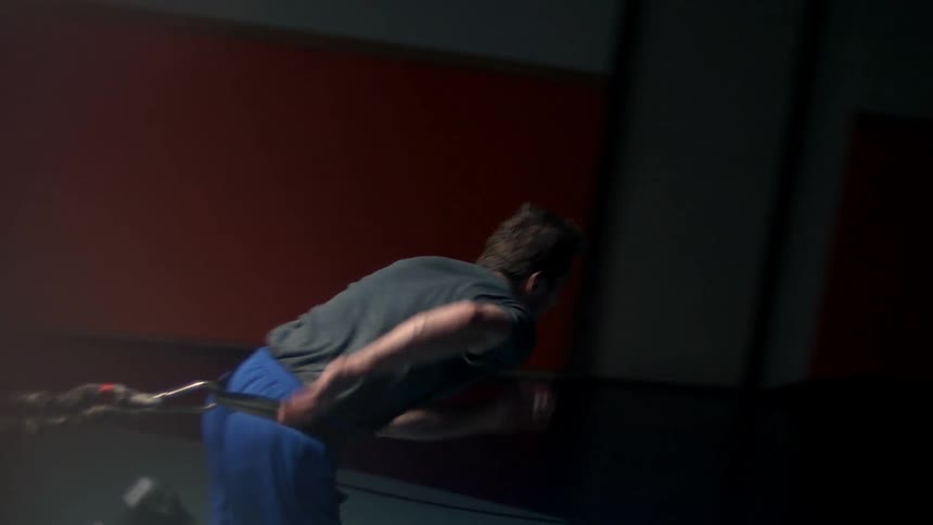 A man in blue shorts runs with a bungee cord attached to his belt
