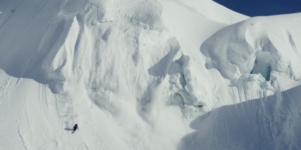 A person skis and airs down a steep mountain