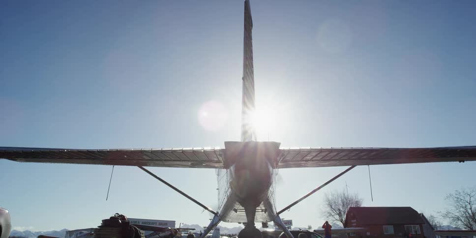 An airplane with its propeller spinning with the sun and the sky in the background