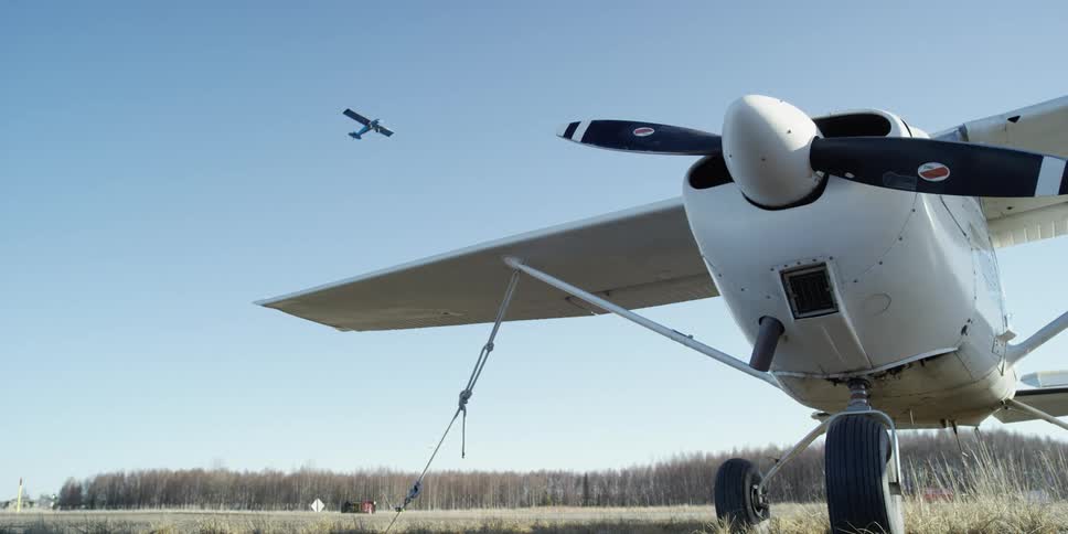 An airplane flies over another plane on the land