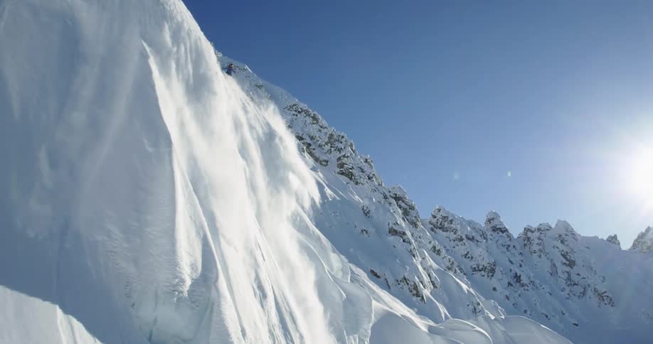 Aerial of skier starting small avalanche in big mountains