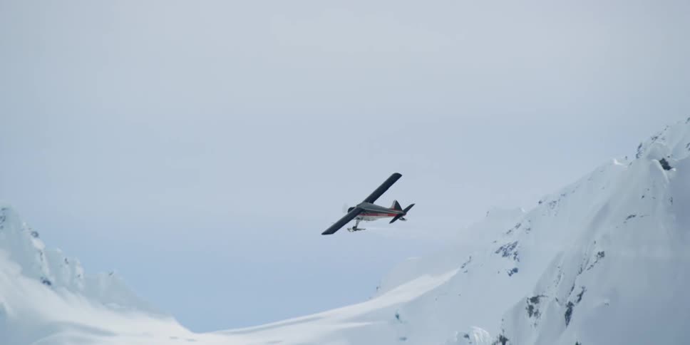 Private small airplane flying through snow covered mountain tops