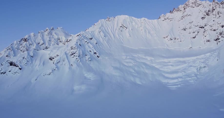 A snow covered mountain ridge and slope in shade