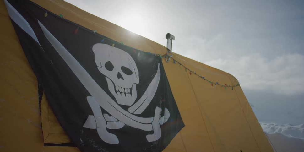 A pirate flag on the side of a tent outdoors in the winter